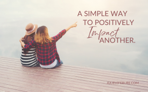 Simple Way to Positively Impact Another | two women sitting on dock, one pointing away