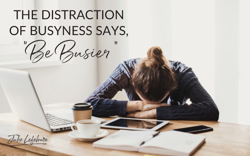 The Distraction of Busyness Says, "Be Busier" | woman sitting with head on a full desk