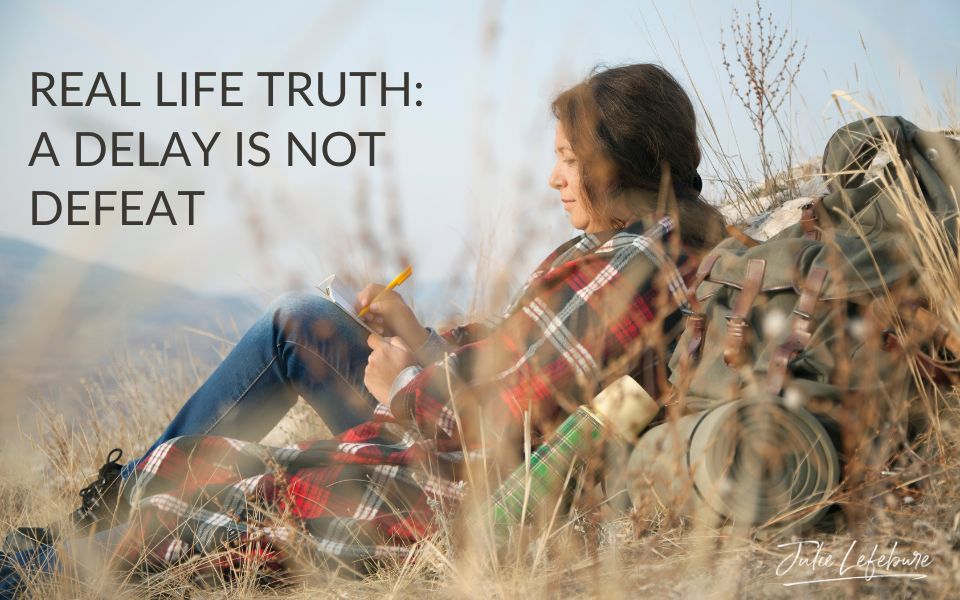 Real Life Truth: A Delay Is Not Defeat | woman in plaid jacket and jeans sitting writing in a journal