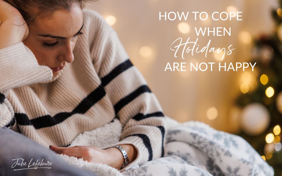 How to Cope When Holidays Are Not Happy | woman under blanket in chair looking sad by a Christmas tree