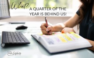 What? A Quarter of the Year Is Behind Us! | woman sitting at desk writing in planner